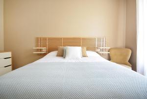a bedroom with a large white bed and a chair at Roma's Apartment in Cambados