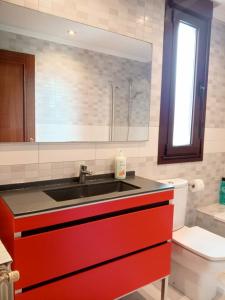 Apartamento Familiar SARDINERO RH 20 في سانتاندير: حمام مع حوض احمر ومرحاض