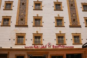 a tall white building with a red sign on it at Best Trip Serviced Apartments in Jeddah