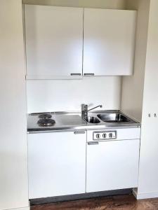 a kitchen with a sink and white cabinets at Ekhult Apartments - Ground Floor - Garden and Lake View in Ulricehamn