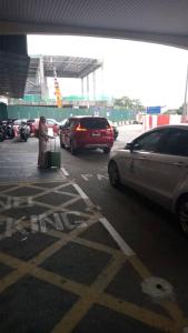 una mujer con una maleta en un estacionamiento con coches en Airport Kota Bharu Roomstay & Riverside Homestay, en Kota Bharu