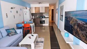 a living room with a couch and a kitchen at BLUE BAY PARADISE - Beach front apartment with sea view in Playa Paraiso