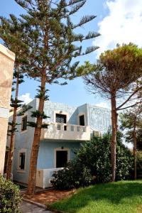Biały dom z drzewami przed nim w obiekcie Niros Beachfront Aparthotel w mieście Kokkini Hani
