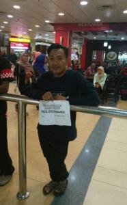 un hombre parado detrás de una barandilla sosteniendo una señal en Airport Kota Bharu Roomstay & Riverside Homestay en Kota Bharu