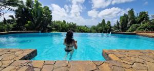 una mujer parada en el agua en una piscina en La Villa Ankarena Location de villa entière avec piscine privée à débordement sur parc aménagé Wifi TV Plage à 5 minutes à pied en Isla Santa María