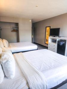 una camera d'albergo con due letti e una televisione di Heritage House Inn a Hyannis