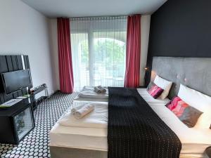 ein Hotelzimmer mit 2 Betten und einem TV in der Unterkunft Hotel Bonvino Badacsony in Badacsonytomaj