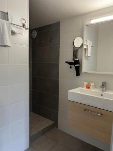 een badkamer met een wastafel en een spiegel bij Hotel Cote et Lac in Biscarrosse