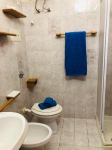 een badkamer met een toilet en een douche met een blauwe handdoek bij Villetta Bouganville vista mare in Porto Ottiolu
