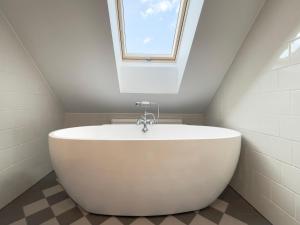 a white bath tub in a bathroom with a window at Karlamuiza Country Hotel in Kārļi