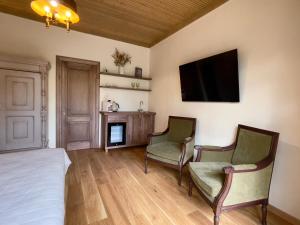 a bedroom with two chairs and a television on the wall at Karlamuiza Country Hotel in Kārļi