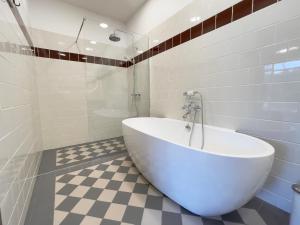 a white tub in a bathroom with a checkered floor at Karlamuiza Country Hotel in Kārļi