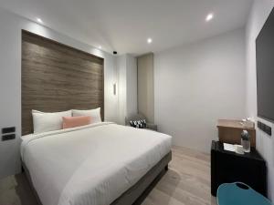 1 dormitorio con cama blanca y pared de madera en 侎雅行旅 台中捷運站館 Mya INN, en Taichung