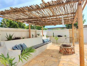 a patio with a bench under a wooden pergola at Luxury White Villa in Nungwi