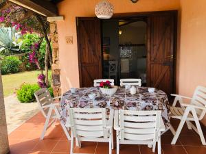 een tafel met witte stoelen eromheen op een patio bij Villetta Bouganville vista mare in Porto Ottiolu