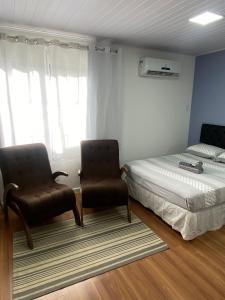 a bedroom with two chairs and a bed and a window at RCM Vilas - Studio 103 Deluxe in Joinville
