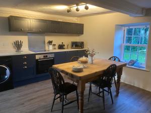 a kitchen with a wooden table and chairs in a kitchen at The Cottage in Exeter