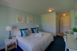 Keurbooms River Lodge 21 في كوربومستراند: غرفة نوم بسرير ابيض كبير بجدران زرقاء