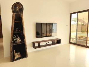 a room with a mirror and a tv on a wall at Luxury White Villa in Nungwi