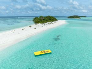 a yellow boat in the water on a beach at Stay Mikado in Thimarafushi