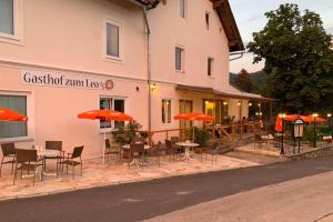 un ristorante con tavoli, sedie e ombrelloni di fronte a un edificio di Gästehaus Leo a Bodensdorf