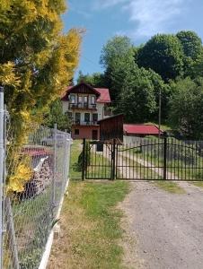 a house behind a fence with a gate at Skalny domek in Krościenko