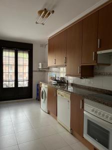 a kitchen with wooden cabinets and a washer and dryer at Apartamento Casa Güelu in Arenas de Cabrales