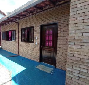 a brick house with a black door and windows at Tahoma Chalé Rustico Lila Prumirim in Ubatuba