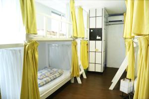 a room with two bunk beds with yellow curtains at Little Asia Guest House in Naha +30 photos