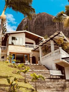 a house with palm trees in front of a mountain at Hotel Casa Linda Guatape in Guatapé