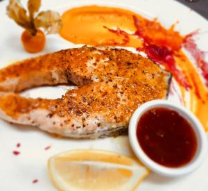 een bord met vis, saus en citroenschijfjes bij Hotel Fieri in Fier
