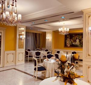 a dining room with tables and chairs and chandeliers at Hotel Fieri in Fier