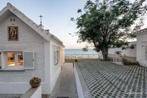 a white house with a tree next to the ocean at La Torre Verde, Villa EN la playa, El Puerto de Santa María in Inmaculada