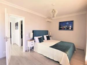a white bedroom with a large bed and a table at Casa Tulipa Ferias - Vilamoura in Quarteira +8 photos