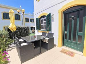 a patio with a table and chairs next to a building at Casa Tulipa Ferias - Vilamoura in Quarteira