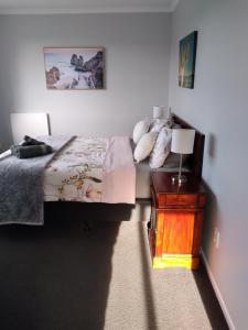 1 dormitorio con 1 cama y 1 mesa con lámpara en My Place, en Hokitika