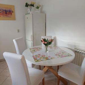 a white dining room table with a vase of flowers on it at Apartment Meli Varazdin in Varaždin