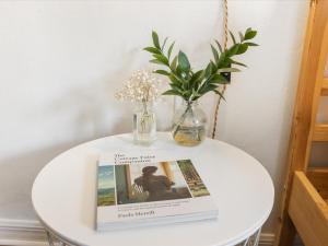 a table with a book and a vase with flowers on it at Convenient & Inviting - Fully-Equipped 2BD Condo in Gainesville