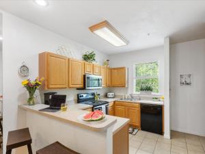 a kitchen with wooden cabinets and a counter top with a bowl of watermelon on at Convenient & Inviting - Fully-Equipped 2BD Condo in Gainesville