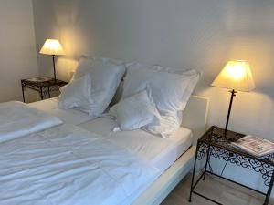 a bed with white pillows and two tables with lamps at Haus Dürresbach in Hennef