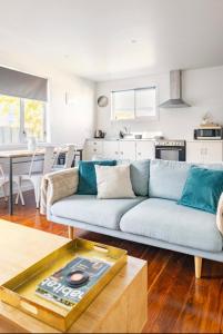 ein Wohnzimmer mit einem blauen Sofa und einer Küche in der Unterkunft Sunny Modern Cottage - Close to Airport in Napier