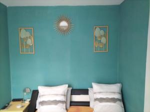 um quarto com uma parede azul com uma cama e um espelho em Chambre double à 10 minutes de Paris em Antony