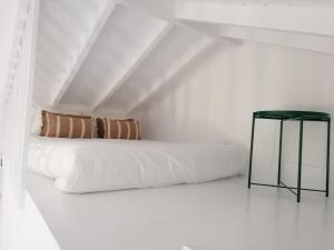 a white room with a bed and a black table at T0 com mezanino à beira-mar in Madalena