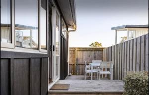una terraza con mesa y sillas en una casa en Sunny Modern Cottage - Close to Airport, en Napier