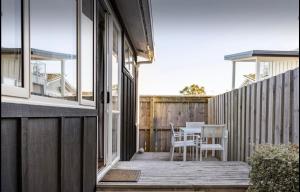 a deck with a table and chairs on a house at Sunny Cottage - Close to Airport & Beach in Napier