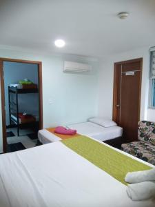 a hotel room with two beds and a chair at Hotel Najjez in Villavicencio