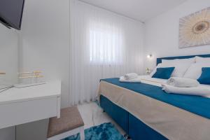 Dormitorio blanco y azul con cama azul en Apartments Menalo Elegance, en Zaton 30 fotos más