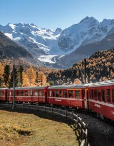 Un train rouge traverse les montagnes. dans l'établissement Dimora Perla di Villa - Historical Wine Retreat near Bernina Express, à Villa di Tirano