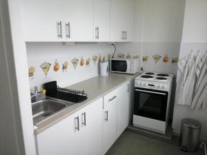 a white kitchen with a sink and a microwave at Római-Víztorony Apartman in Dunaújváros