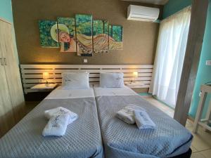 two beds in a hotel room with towels on them at Lazy Lizard in Néa Karváli